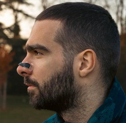Man using Magnose™ magnetic nose strip outdoors to improve breathing quality.